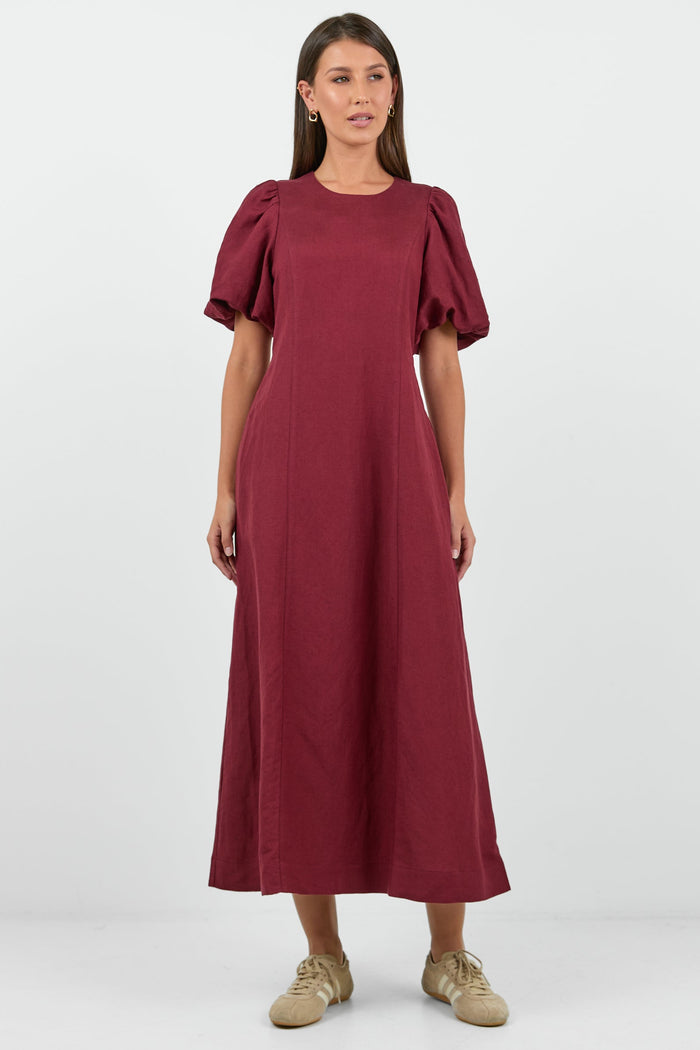 Woman wearing a burgundy dress with ruffled sleeves on a white background