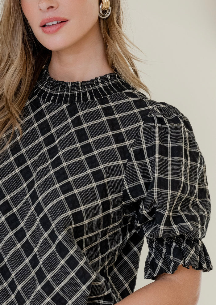 Model wears a black check top with black jeans