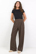 Woman wearing a black top and brown wide-leg pants on a white background