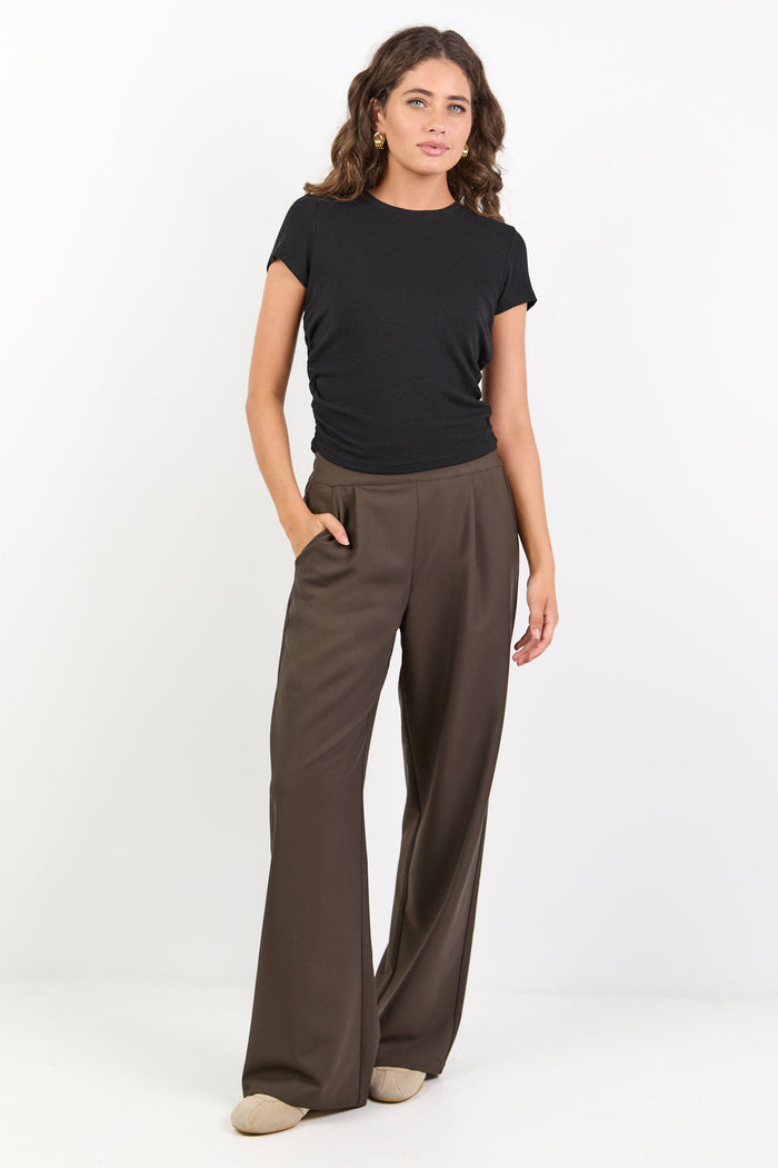 Woman wearing a black t-shirt and brown wide-leg pants on a white background