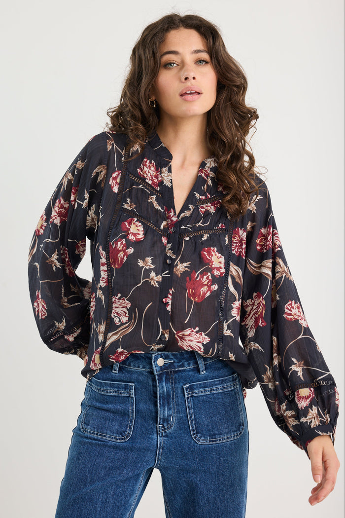 Woman wearing a floral blouse and blue jeans on a white background