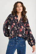 Woman wearing a floral blouse and blue jeans on a white background