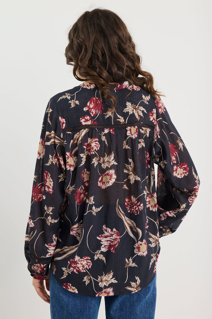 Person wearing a floral blouse with long sleeves on a white background
