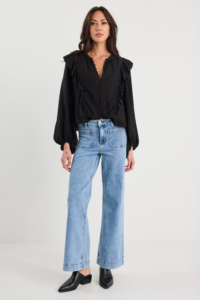Woman wearing a black blouse and blue jeans on a white background