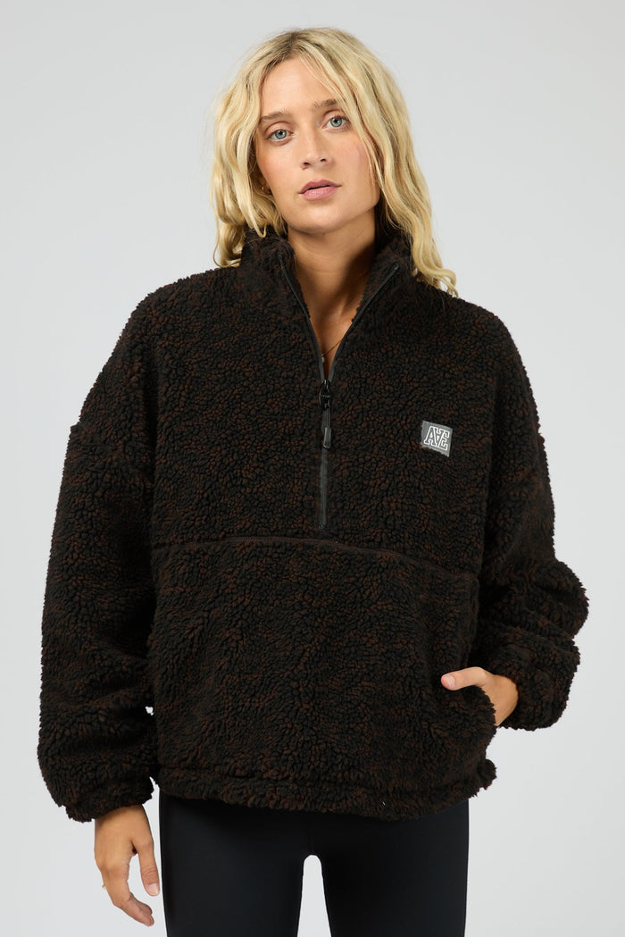 Person wearing a black fleece pullover with a logo on a gray background