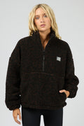 Person wearing a black fleece pullover with a logo on a gray background