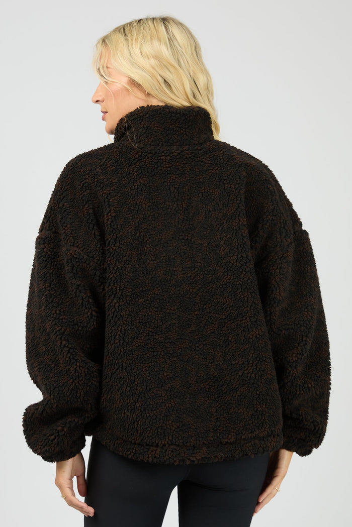 Person wearing a dark brown fleece jacket on a plain background