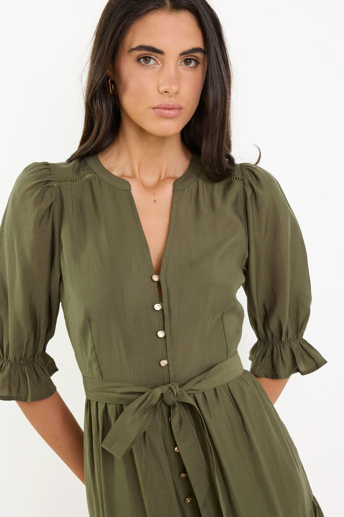 Woman wearing a green dress with puffed sleeves on a white background