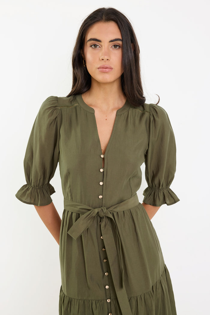 Woman wearing an olive green dress with puff sleeves on a white background