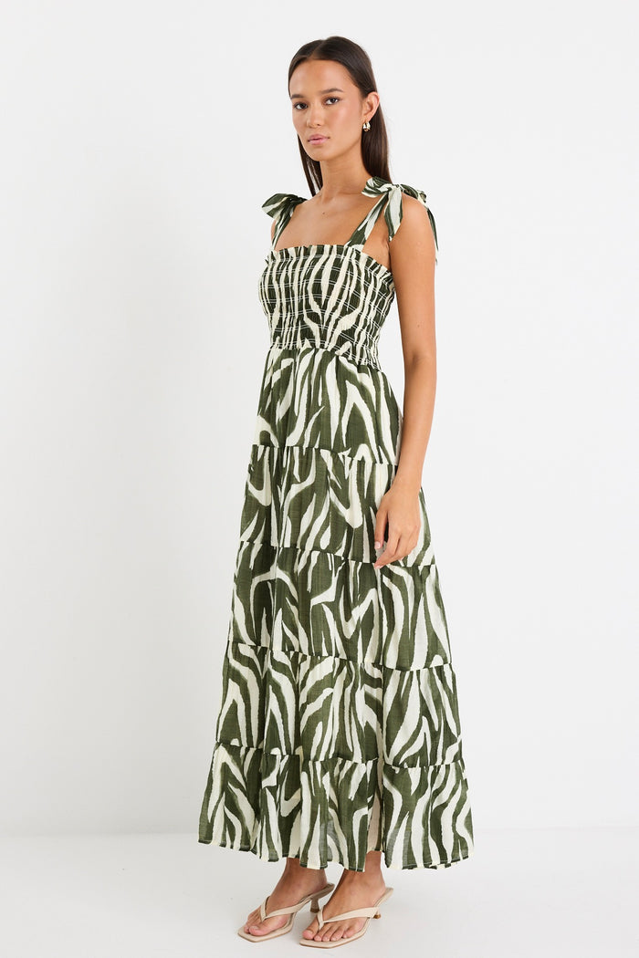Model wearing a bold khaki zebra print dress with strappy tie details, a shirred bodice, and a tiered design.