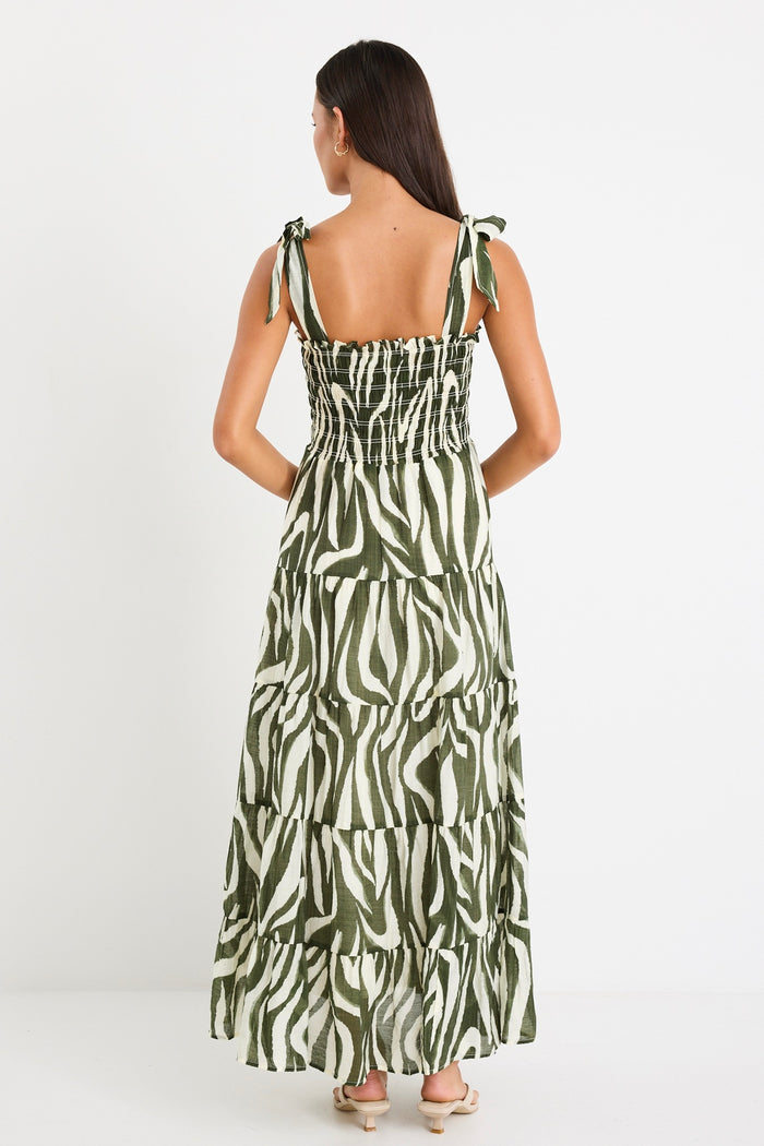 Model wearing a bold khaki zebra print dress with strappy tie details, a shirred bodice, and a tiered design.