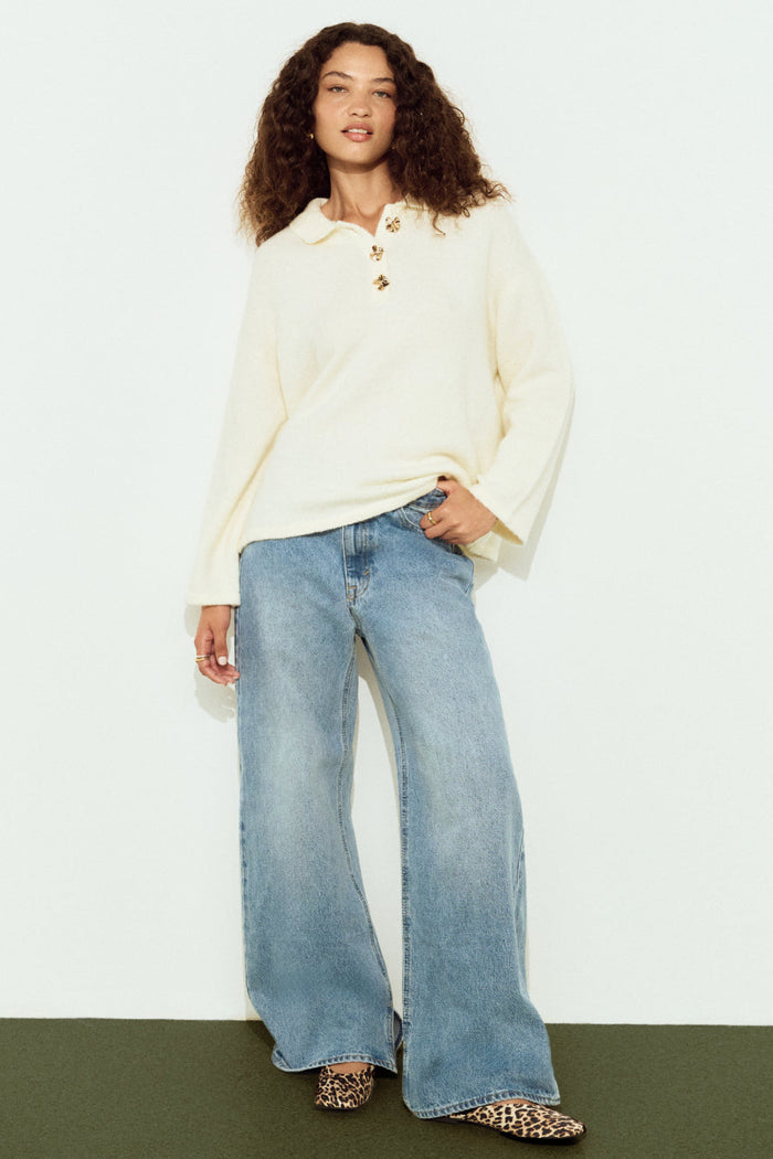 Woman wearing a white blouse and blue jeans against a white background