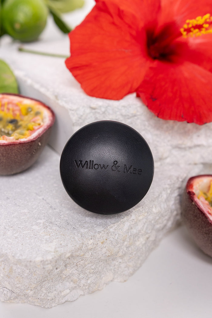 Black ball with 'Willow & Me' branding on a stone surface with a red flower and passion fruit.