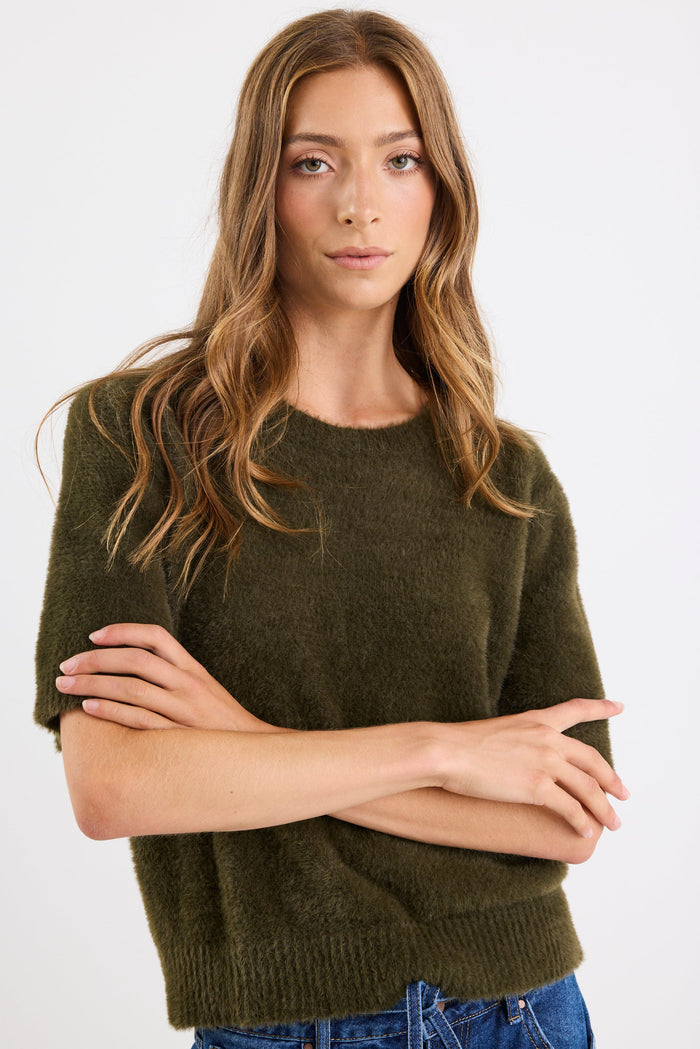 Woman wearing a green sweater against a white background