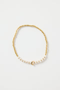 Gold and ivory beaded bracelet with a small gold heart charm in the centre, photographed on a clean white background.
