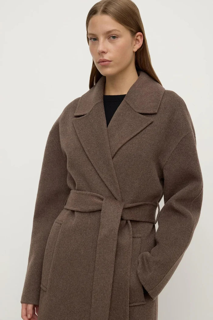 Woman wearing a brown coat against a white background