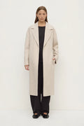 Woman wearing a long beige coat on a white background