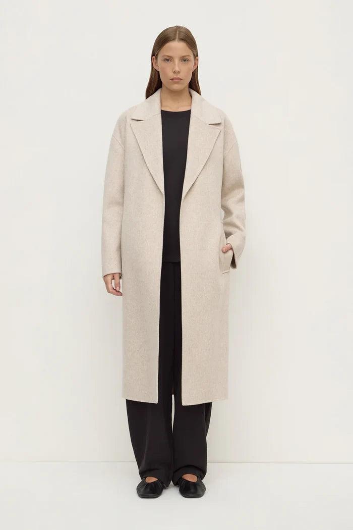 Woman wearing a long beige coat on a white background