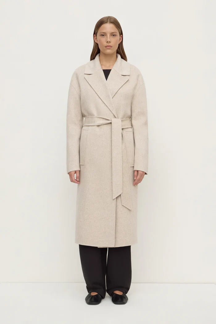 Woman wearing a beige trench coat on a white background