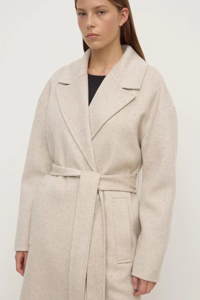 Woman wearing a beige coat on a white background