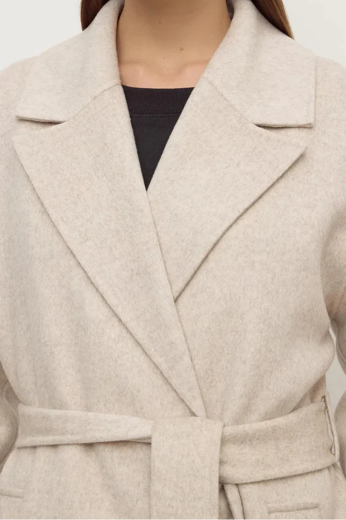 Woman wearing a beige coat against a white background