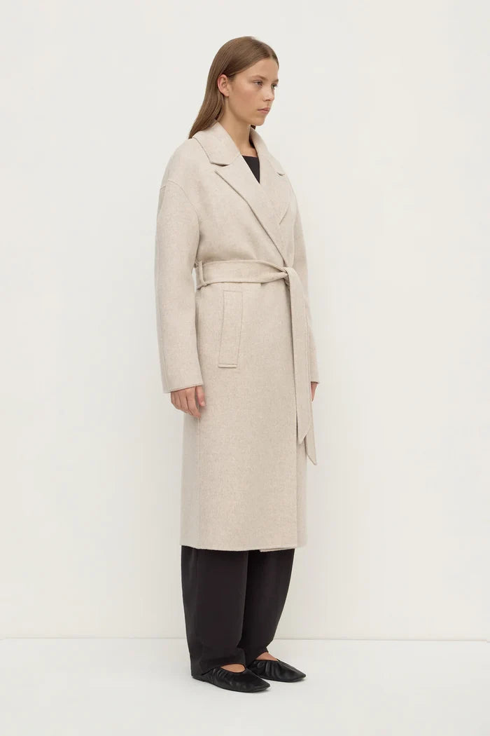 Woman wearing a beige trench coat on a white background