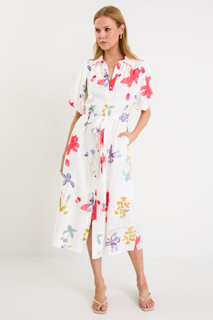 Model wearing a cream midi shirt dress with colourful poppy floral print, puff sleeves and a waist tie.