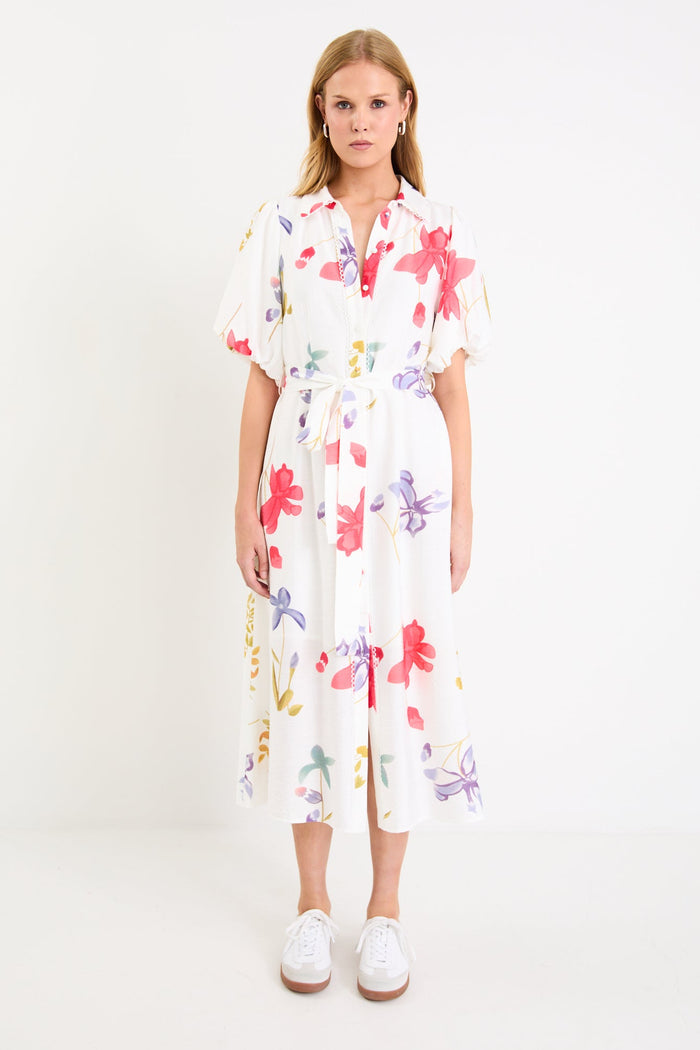 Model wearing a cream midi shirt dress with colourful poppy floral print, puff sleeves and a waist tie.