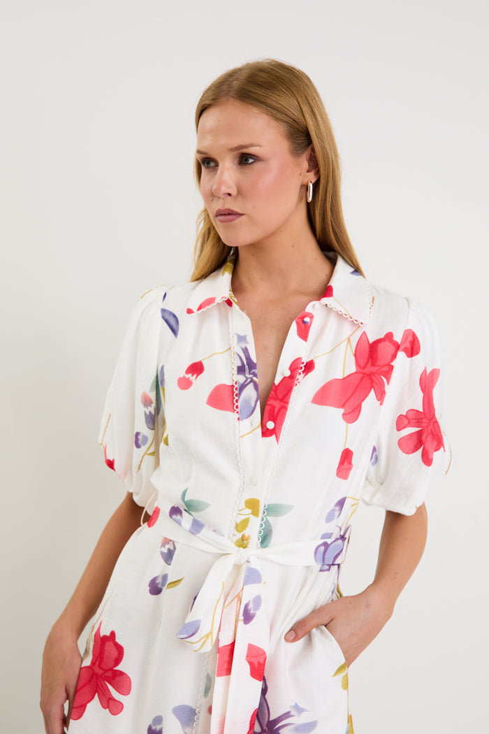 Model wearing a cream midi shirt dress with colourful poppy floral print, puff sleeves and a waist tie.