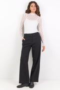 Woman wearing a white lace top and black pants on a white background