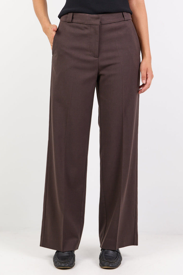 Person wearing brown wide-leg pants and a black top on a white background