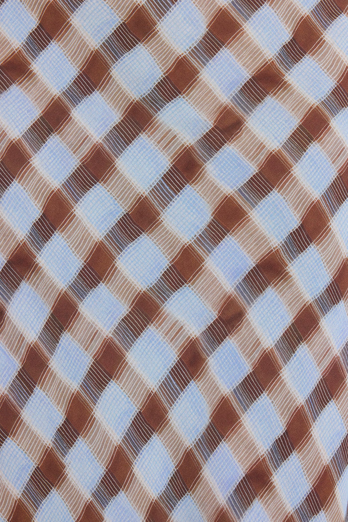 A close-up of a woven fabric with a diagonal diamond check pattern in brown, beige, and light blue.
