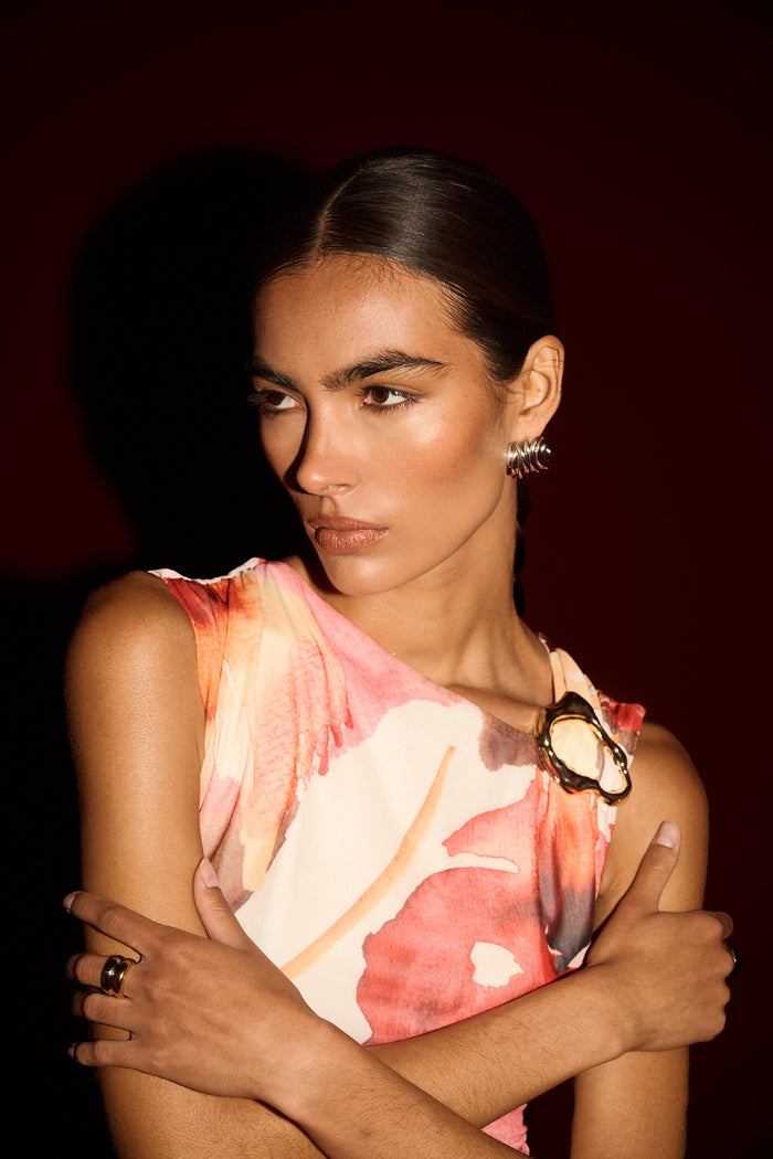 Woman wearing a sleeveless floral top with a dark background