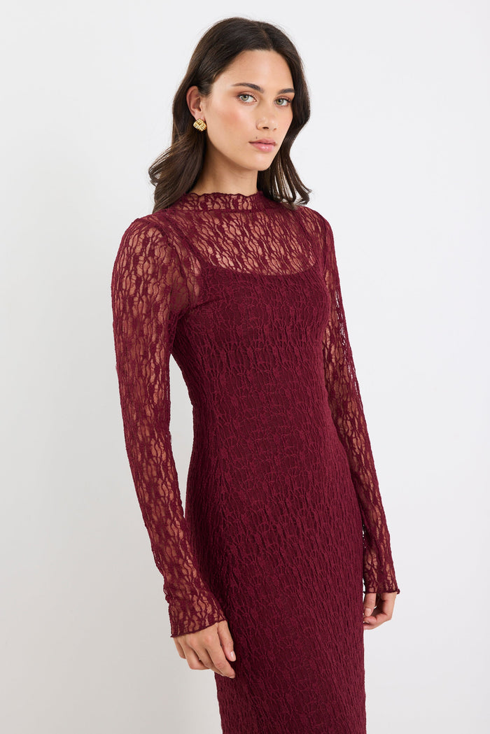 Woman wearing a burgundy lace dress against a white background