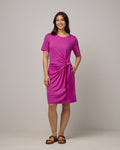 Model wearing Kelly Faux Tie Dress in Petunia, a bright fuchsia pink color. Kelly Faux Tie Dress is a merino wool crew neck, short sleeve, knee length shift dress with pockets available in sizes XS-3X.