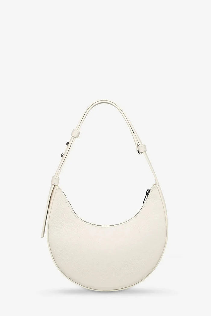An off-white crescent-shaped leather shoulder bag with a single adjustable strap, displayed against a clean, light gray background.