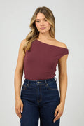 Woman wearing a burgundy one-shoulder top and blue jeans on a white background