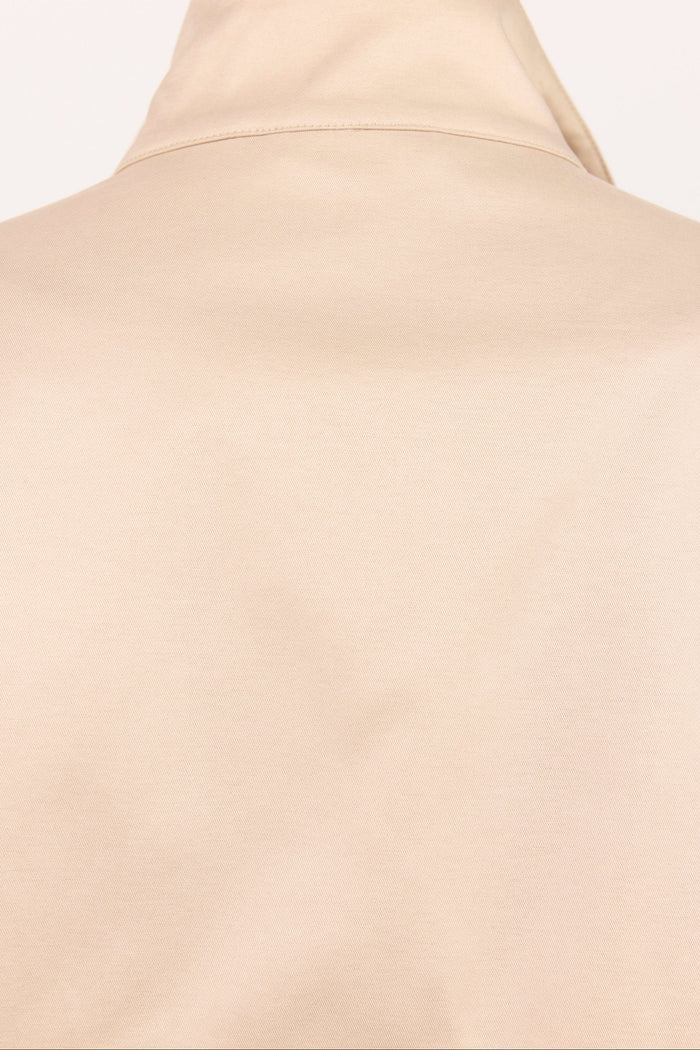 Close-up of a beige or cream-colored garment, showing the back of a high-neck top or turtleneck with a smooth matte finish.
col_pattern