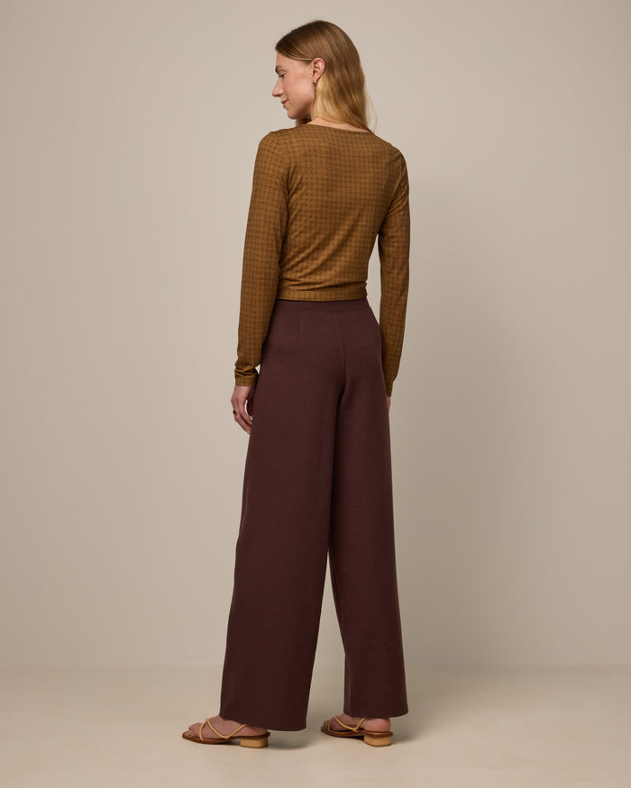Model wearing Lane Wide Leg Ponte Pant in Espresso, a warm brown color. Lane Wide Leg Ponte Pant is a merino wool pant with pockets available in sizes XS-3X Regular, XS-XXL Long.