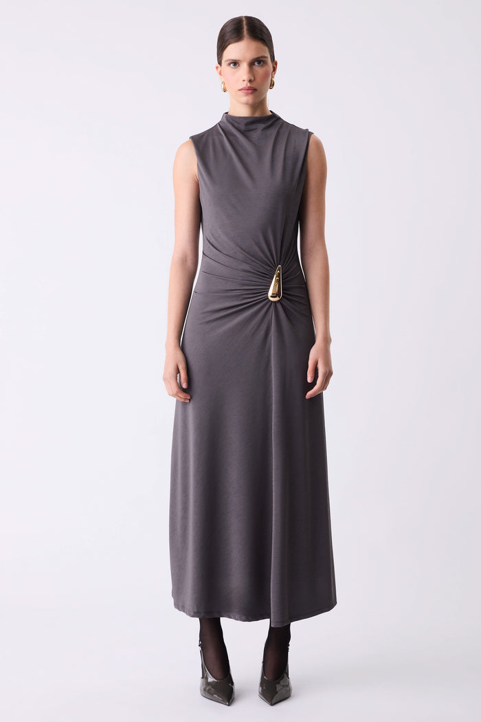 Woman wearing a sleeveless gray dress with a gold belt on a white background
