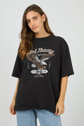 Woman wearing a black t-shirt with an eagle graphic and text on a plain background
