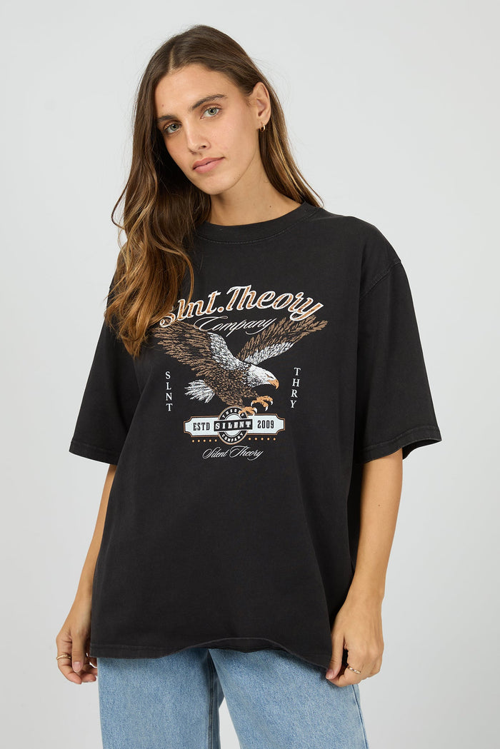 Woman wearing a black t-shirt with an eagle graphic and text on a plain background