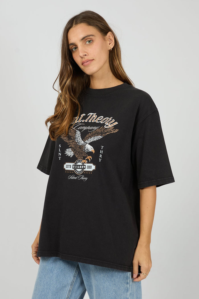 Woman wearing a black t-shirt with an eagle graphic design on a plain background