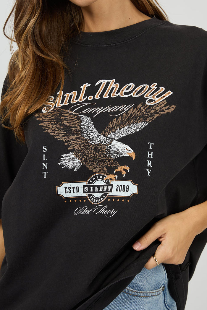 Person wearing a black t-shirt with an eagle graphic and text on a plain background