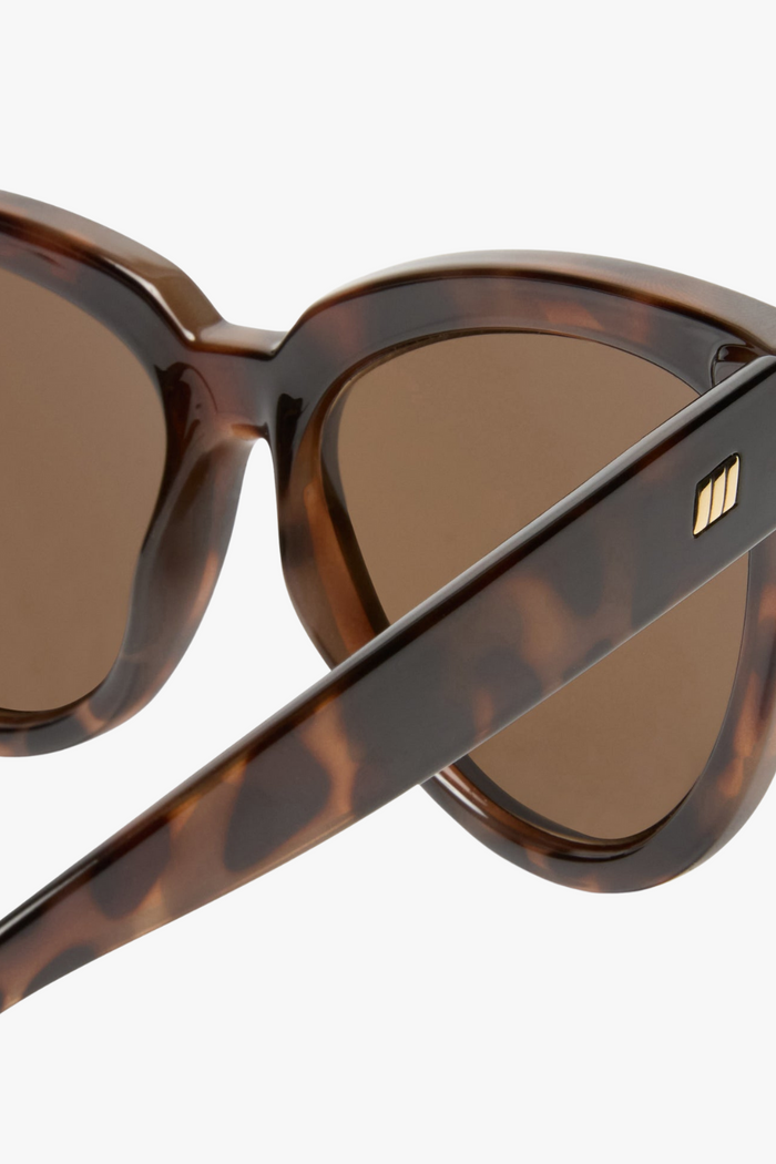 Front-facing view of oversized cat-eye sunglasses in a glossy tortoiseshell frame with warm brown lenses. The bold, sculpted silhouette adds a vintage-inspired edge with a modern twist.
