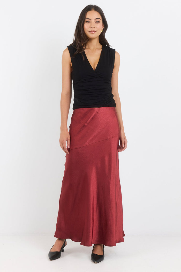 Woman wearing a black sleeveless top and red skirt on a white background