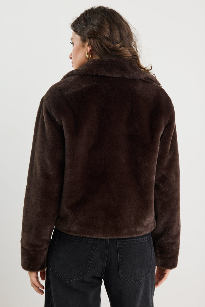 Person wearing a brown jacket from behind on a white background