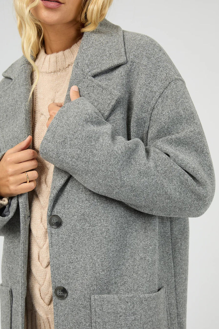 Person wearing a gray coat with a neutral background