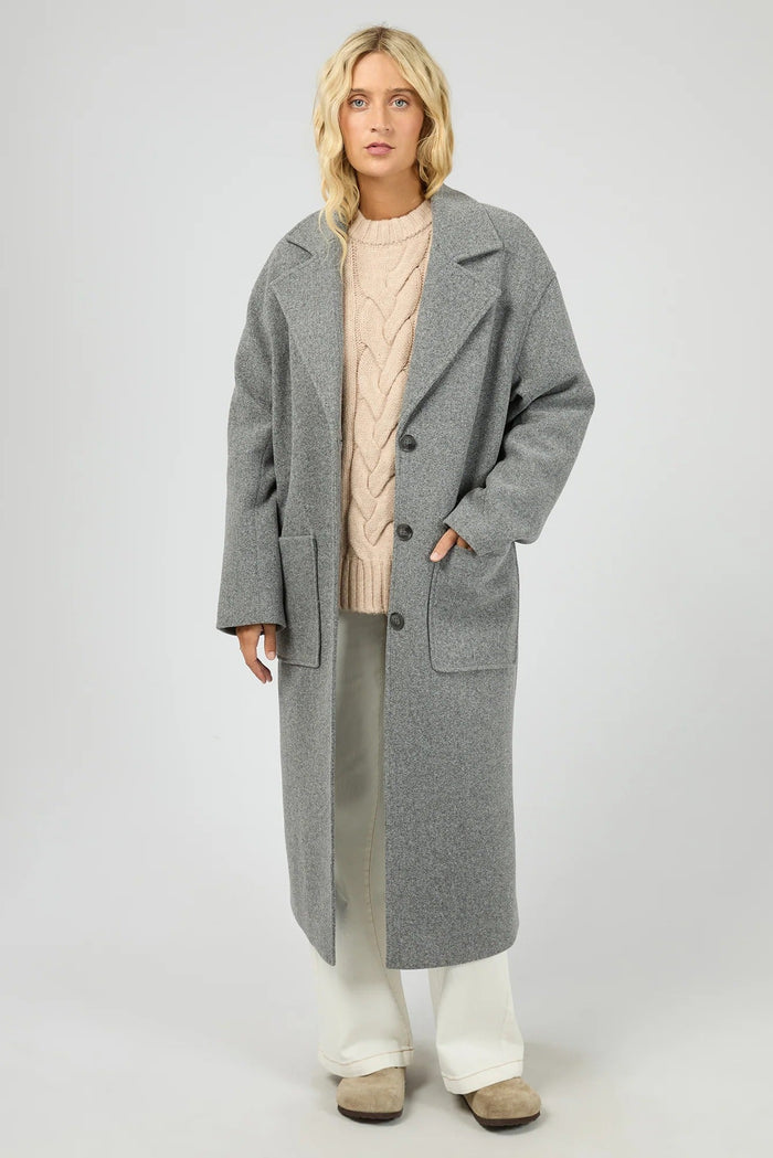 Woman wearing a long gray coat on a white background
