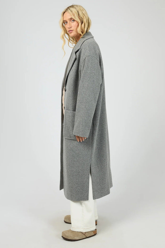 Person wearing a long gray coat on a white background